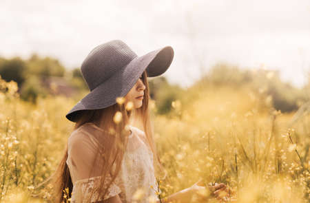 A girl with long hair holds a bouquet of yellow flowers. Rape field. close-upの写真素材