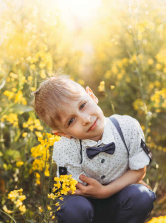 little cute boy in an oilseed rape field. Rural landscape. Verticalの写真素材