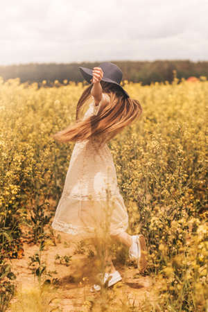Portrait of a beautiful young girl in a hat against the background of a rapeseed field.の写真素材