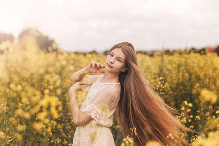 Portrait of a beautiful young girl in a hat against the background of a rapeseed field.の写真素材