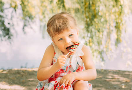 Little cute funny girl licking lollipop