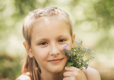 A little girl holds a white rabbit in her arms in nature in the summerの写真素材