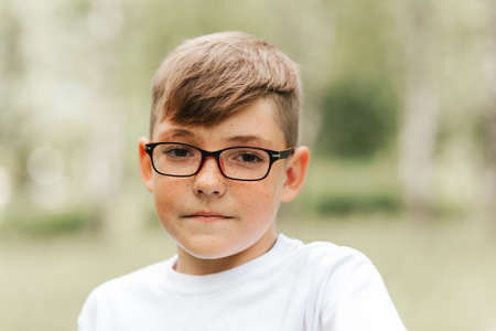 Funny boy with freckles and glasses shows a sign of class in nature. Positive children's emotionの写真素材
