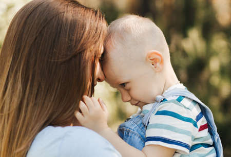 A young mother plays with her young son in the park in the summerの写真素材