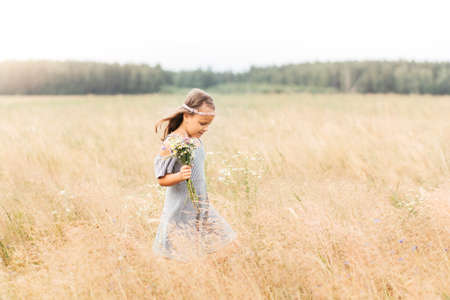 Cute smiling little girl with flower wreath on the meadow. Portrait of adorable small kid outdoors.の写真素材
