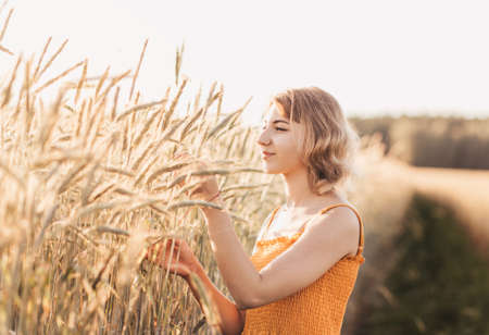 Young beautiful girl with a bouquet of daisies in a wheat fieldの写真素材