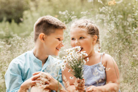 Boy and girl, brother and sister in nature in the summer hugging and playingの写真素材