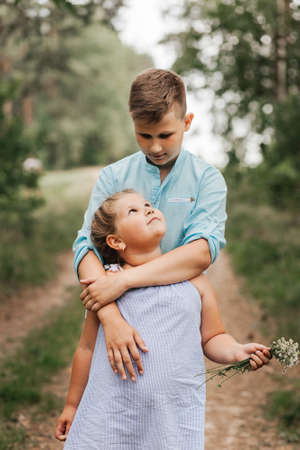Boy and girl, brother and sister in nature in the summer hugging and playingの写真素材