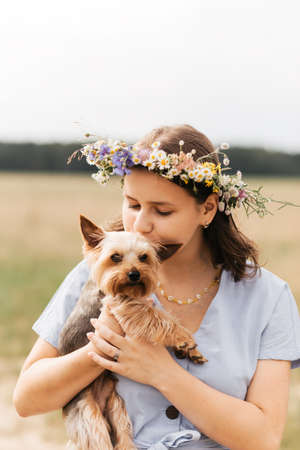 The girl holds a small Yorkie dog in nature in the summer. Kids and pets.の写真素材