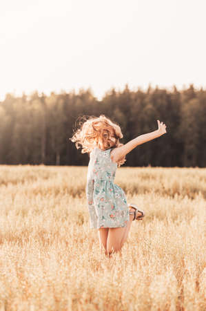 A happy little girl runs through a wheat field in the summer on a sunny day. Summertime. Summer vacation. Happy childhood. Positive emotions and energyの写真素材