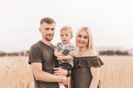 Beautiful family parents and a young son in a wheat field. Mom, Dad and Baby Together. Happy family,...
