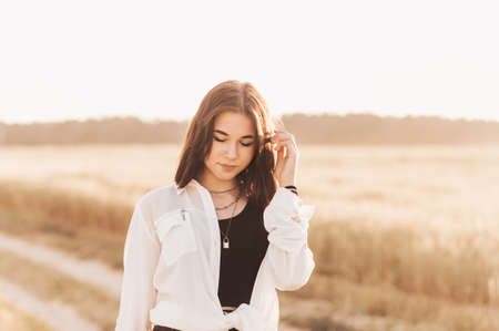 Teenage girl walks alone in nature in the summer. Schoolgirl with black hair relaxingの写真素材