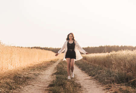 Teenage girl walks alone in nature in the summer. Schoolgirl with black hair relaxingの写真素材