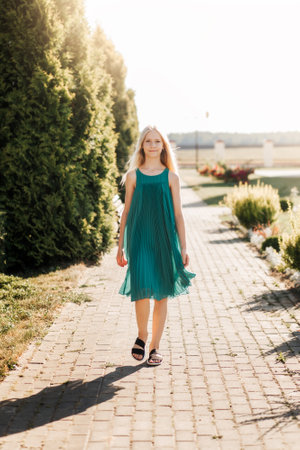 Beautiful teenage girl with long white hair walking through a wheat field on a sunny dayの写真素材
