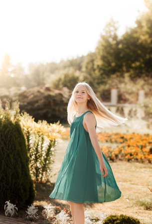 Beautiful teenage girl with long white hair walking through a wheat field on a sunny dayの写真素材