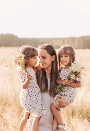 Mom with two twin girls playing in nature in the summerの写真素材