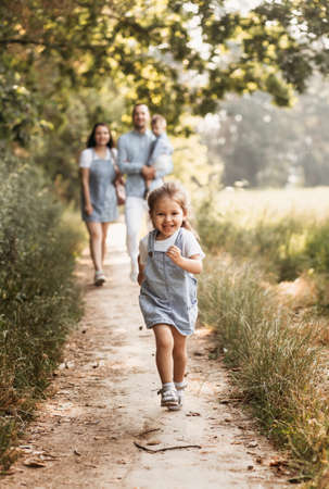 Young happy family with two children in nature in the summer walk. Healthy Smiling Dad, Mom and kids togetherの写真素材