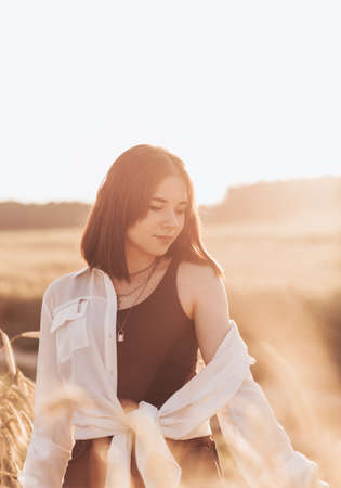Teenage girl walks alone in nature in the summer. Schoolgirl with black hair relaxingの写真素材
