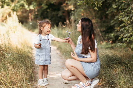 Young happy mother with her little daughter in nature in the summerの写真素材