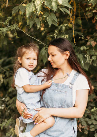 Young happy mother with her little daughter in nature in the summerの写真素材