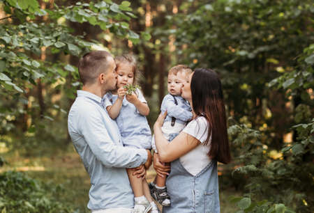 Young happy family with two children in nature in the summer walk. Healthy Smiling Dad, Mom and kids togetherの写真素材