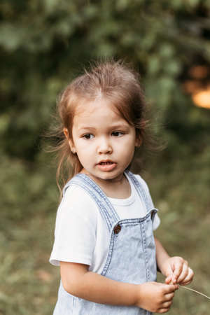 Positive charming little girl enjoying summer sunny day, expression emotions, having fun, happy child walking in summer dayの写真素材