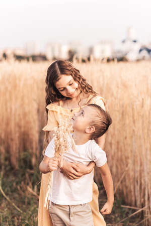 Older sister walks with her brother in nature in the summer. Happy kids sibling walking and playing. Kids play outdoorsの写真素材