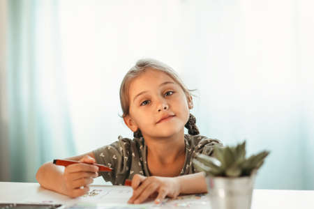 A little girl lies on the carpet in front of a computer screen. Online communication