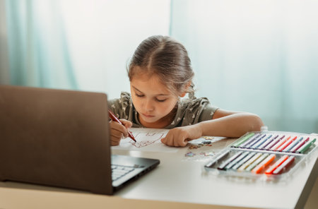 A little girl lies on the carpet in front of a computer screen. Online communicationの写真素材