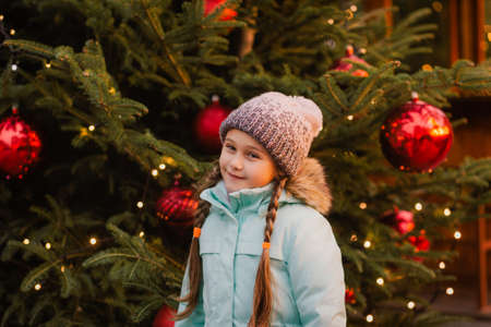 happy little girl at christmas market in winter evening.の写真素材