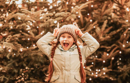 happy little girl at christmas market in winter evening.の写真素材