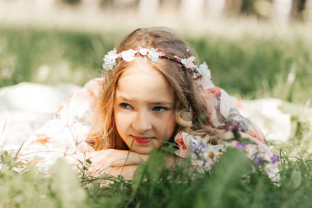 Smiling blonde teen girl posing in summer garden. Wearing flower wreath outdoors.の写真素材