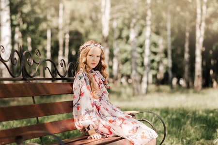 Smiling blonde teen girl posing in summer garden. Wearing flower wreath outdoors.の写真素材
