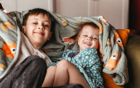 happy teenage boy sitting home on bed, little girl, brother and sister hugging. concept happy...