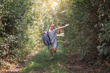 Back to school. A cute little schoolgirl in a dress with pigtails and large blue backpackis walks in...