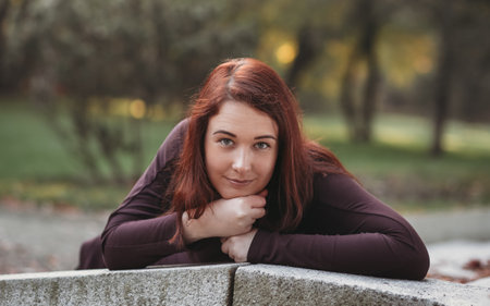 An attractive young woman with a sad pensive expression in a park on a sunny day. Shallow depth of field female creative portraitの写真素材