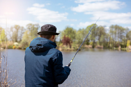 fishing rod on lake water background. Man catching fish by spinning on lakesideの写真素材