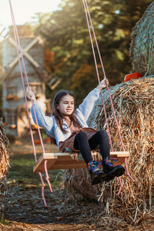 Autumn harvest of pumpkins. Child and orange pumpkin at farm market or seasonal festival. Cute little girl playing among pumpkins. Thanksgiving holiday season and Halloween.の写真素材