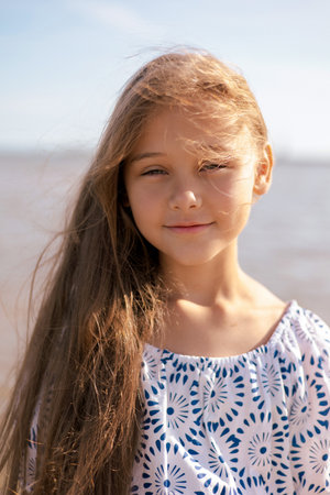 Close up portrait Adorable child girl with long hair outdoors enjoying sunset at beach on summer day. Travel and holidaysの写真素材