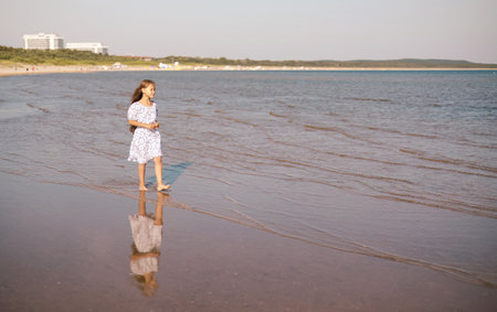 Adorable child girl with long hair outdoors walking and enjoying sunset at beach on summer day. Travel and holidaysの写真素材