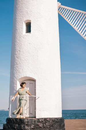Happy senior woman in long dress walking on tropical island beach at summer sunset. Elderly retired woman relax and enjoy outdoor lifestyle activity in summer beach holiday travel vacation.の写真素材