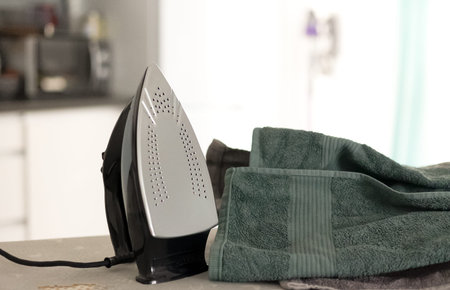 Clothes iron and laundry on an ironing board at home, clean domestic scene, everyday household...