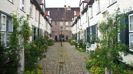 Beautiful cozy courtyard with old houses and flowers in the street of old town, Lubeck