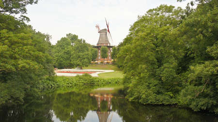 View of landscape with old windmill in the park with pond, city garden, Bremen