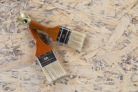 two brushes are prepared for repair and painting, lying on wooden plateの写真素材