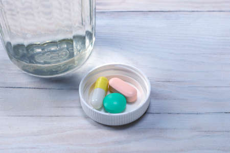 Daily doses of tablets for patients for each day on wood table background.