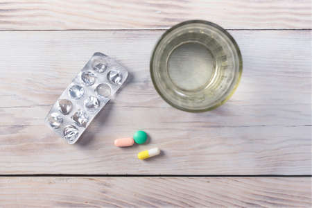 Daily doses of tablets for patients for each day on wood table background.
