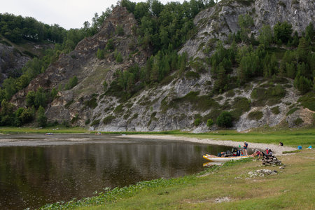 Group of people relax on shore during canoe rafting on river. Tourists rafting down or floating on mountain river.のeditorial素材