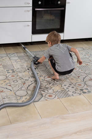 pre-school boy does homework, vacuums floor. Help parents at homeの写真素材