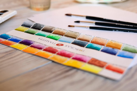 Set of multicolored watercolor palette and brushes on wooden table. Selected focus Russia, Omsk, April 2020.のeditorial素材